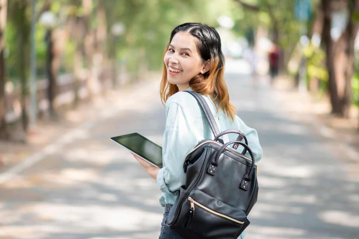 studentessa cammina su un viale alberato