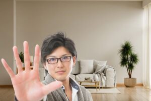 divano con pianta vicino e uomo in primo piano che fa segno di stop