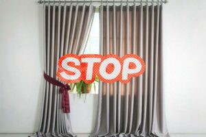 scritta stop su una finestra con la tenda