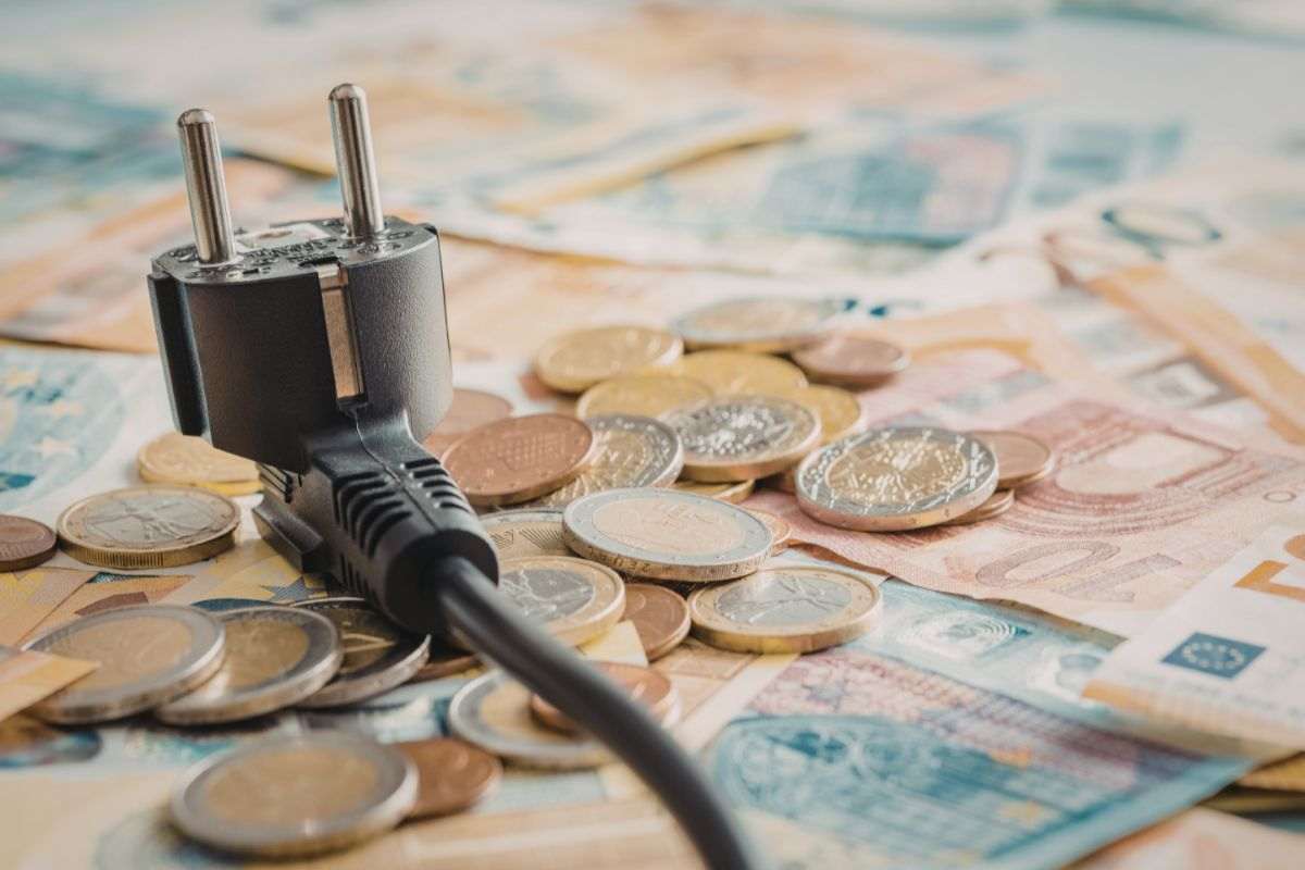 presa elettrica poggiata su soldi in contanti e spiccioli