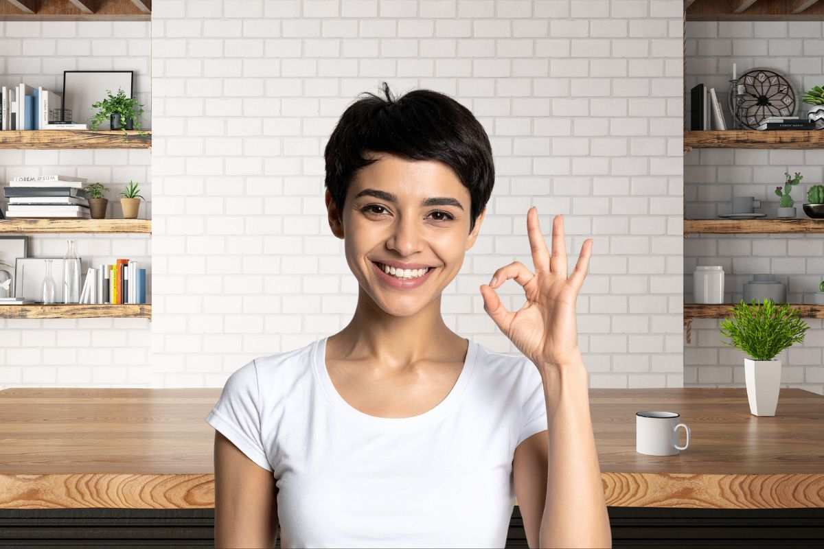 donna che fa ok e come sfondo una cucina con delle mensole