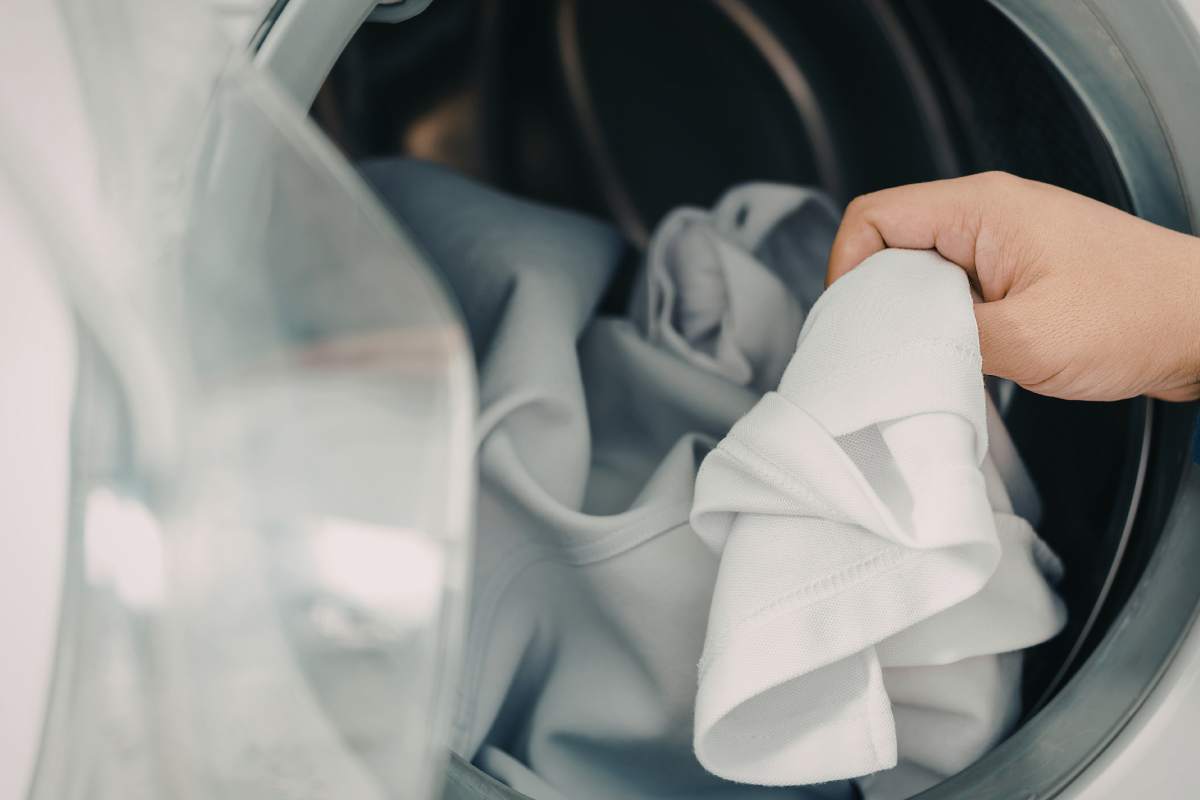 mano che prende panni nella lavatrice