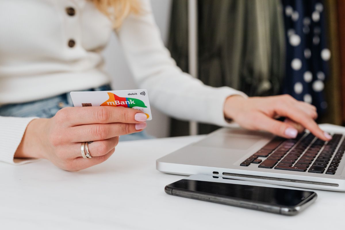 donna con carta di credito in mano che sta al pc