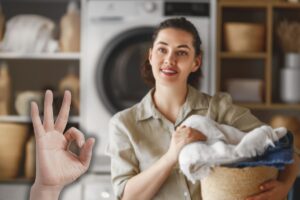 donna con cesta di bucato in mano e mano che fa ok